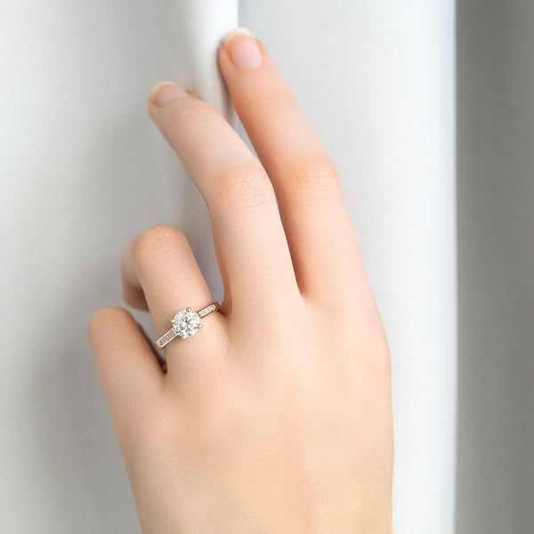 lady wearing round brilliant cut engagement ring  with elegant baguette cut diamond shoulders