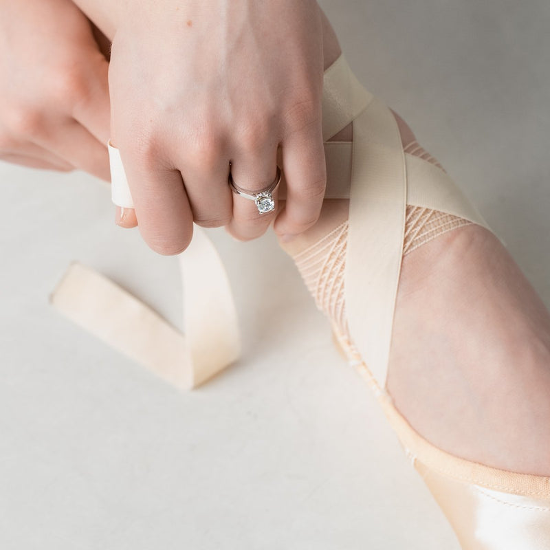 ballerina tying ribbon wearing diamond engagement  ring